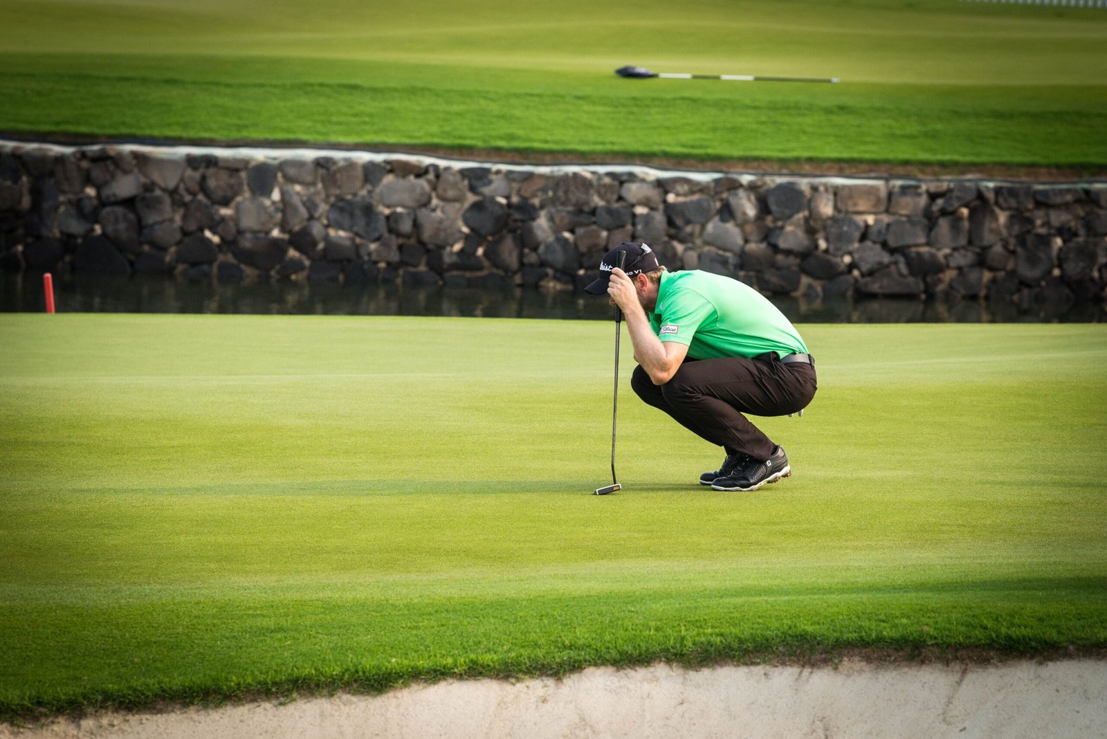 Profesional leyendo la caída del green agachado junto a su putter